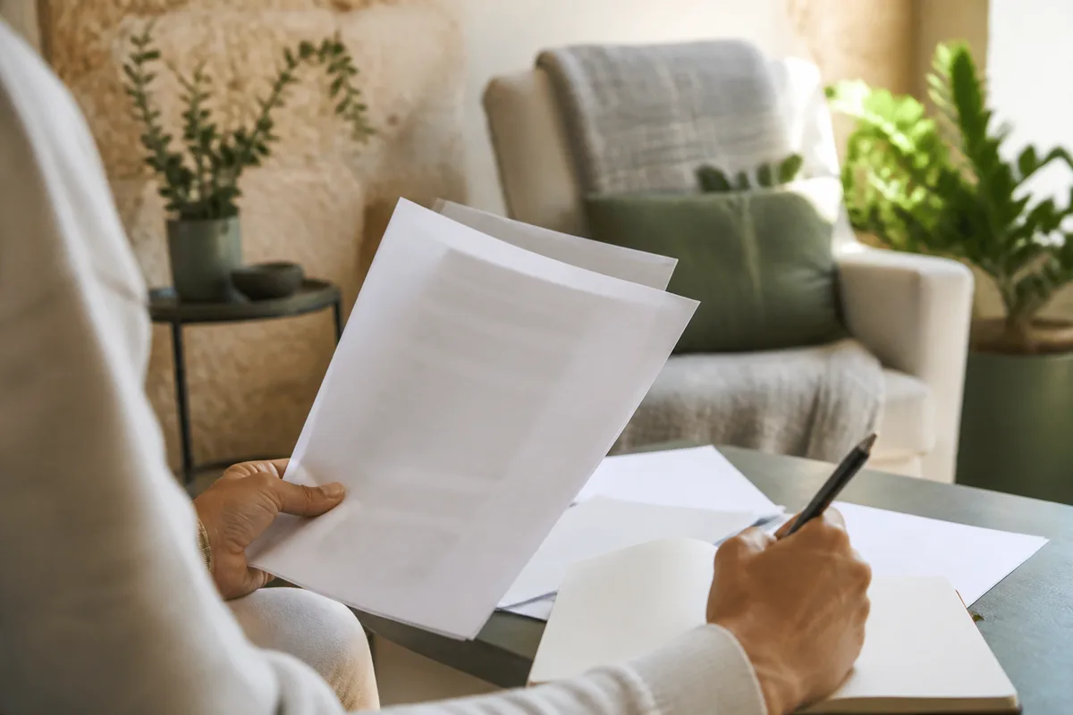 Personne comparant des documents et prenant des notes avant de choisir un praticien
